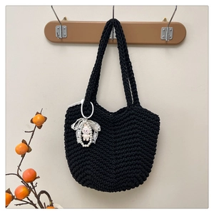 Detail of hand-woven black tote bag with cute rabbit pendant and pearl accessories