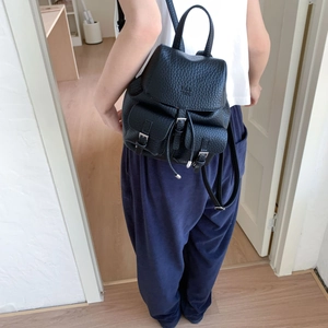 Detailed close-up of a black lychee-grain leather backpack with silver buckles and flap