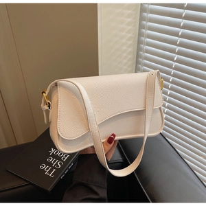 Detail view of white lychee textured shoulder bag with gold hardware and curved flap