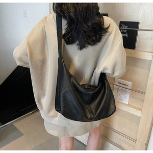 Black pebbled leather hobo bag worn by model, showing its large capacity and sleek shape