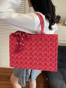 Red tote bag with traditional囍jacquard pattern and ribbon detail on white background
