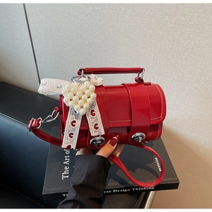 Dettaglio mini borsa bauletto rossa in vernice con ciondolo a perla e nastro di pizzo