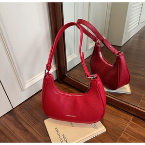 Detail of red pebbled leather hobo bag with silver logo on a minimal indoor background