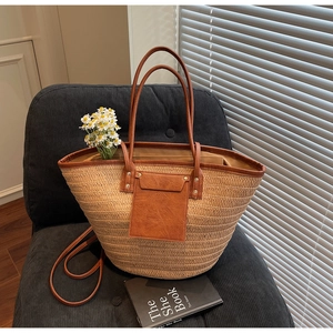 Detail of woven straw tote bag with brown leather pocket on a velvet sofa