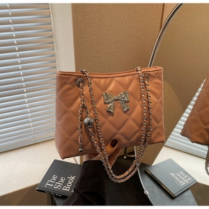 Detail of pink quilted chain bag featuring silver bow hardware and diamond stitching