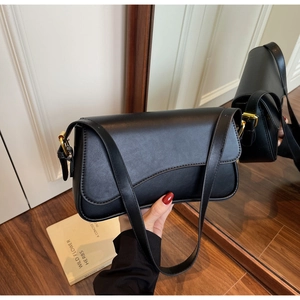 Détail d'un sac sous le bras en cuir noir avec boucle dorée et rabat incurvé élégant