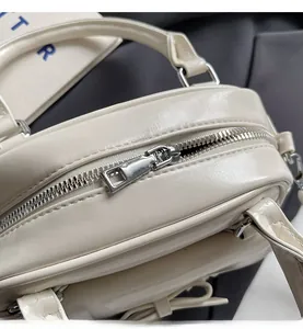 Detail of silver zipper closure and leather bow on creamy white ballet style handbag