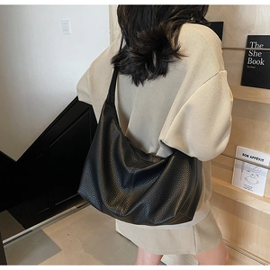 Detailed view of black litchi pattern leather hobo bag on shoulder for daily commute