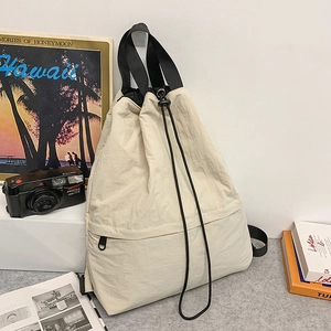 Detailansicht der cremeweißen Kordelzug-Tasche mit schwarzem Gurt in Lifestyle-Umgebung