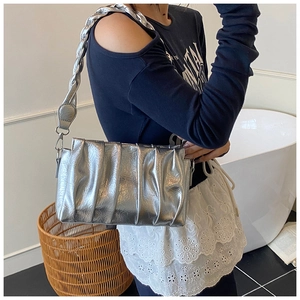 Close-up of metallic silver pleated cloud bag featuring a wide woven shoulder strap
