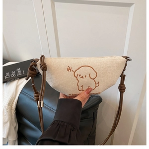 Vue détaillée du tissu beige tissé et de la broderie chiot sur un sac en forme de croissant