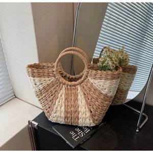 Detailed texture of a woven straw tote bag with metallic threads and circular handles