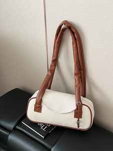 Borsa cilindrica moderna in tessuto crema con finiture in pelle marrone su sedia in pelle