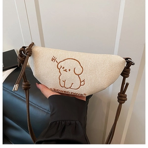 Détail du sac dumpling en toile blanc cassé avec chiot brodé et bandoulière marron