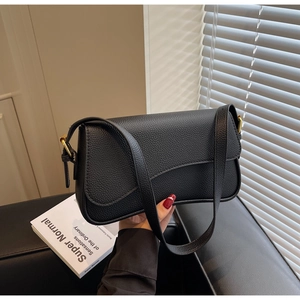 Detail of black lychee grain leather shoulder bag with adjustable golden buckle strap