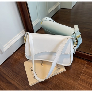 Reflet montrant la boucle latérale et le cuir crème lisse du sac sous les bras