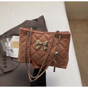 Detail of pink quilted handbag with silver bow charm and elegant metal chain strap