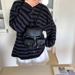 Detail of black pebbled leather mini backpack with metal buckles and silver hardware