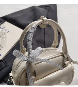 Detail of cream Boston bag handle with gray plaid ribbon bow and durable stitching