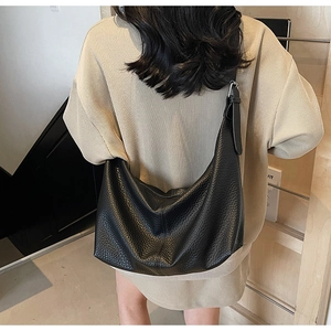 Model wearing a black lychee texture hobo bag with adjustable strap and silver buckles