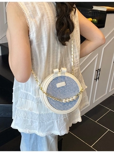 Minimalist round crossbody bag with blue woven texture and pearl chain strap on model