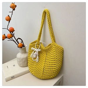 Detail of yellow woven tote bag featuring a cute rabbit charm and pearl lace accessory