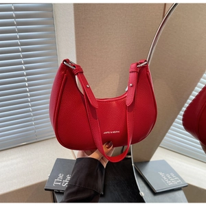 Detail of red crescent hobo bag with litchi texture and silver metal buckle