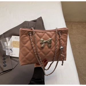 Close-up of pink quilted tote bag featuring a metallic bow and elegant silver chain strap