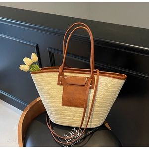 Detail of woven straw tote bag with brown leather trim and pocket on a chair