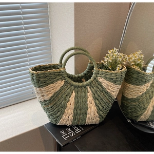 Macro detail of sage green and cream woven straw bag with shimmering gold thread accents