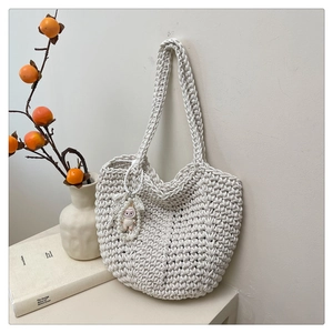 Close-up of tight wave pattern crochet texture on off-white woven tote bag with lace charm