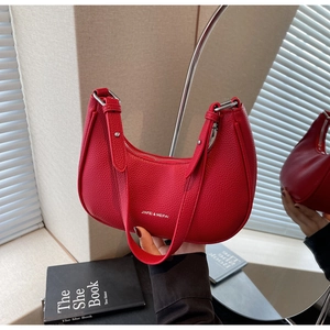 Detail of red lychee grain leather saddle bag featuring silver metal buckle and strap