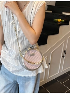 Pink woven round crossbody bag with luxury pearl chain strap and gold hardware accents