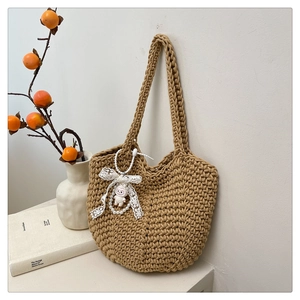 Detail of hand-woven crochet tote bag with lace bow, pearl charm and cute sheep pendant