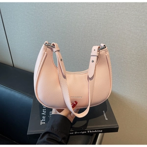 Detail of pink lychee leather hobo bag with silver logo and adjustable shoulder strap
