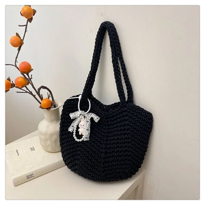 Detail of black woven knit tote bag with lace bow decoration and soft texture