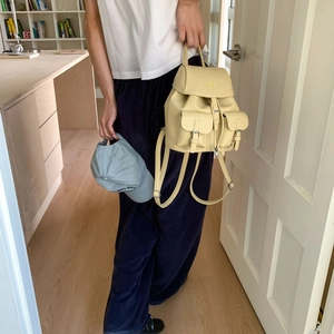 Detailed view of beige leather backpack with drawstring closure and silver buckles