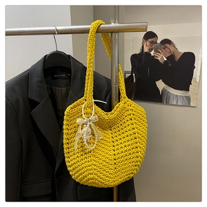 Detail of bright yellow hand-woven crochet bag with pearl and doll accessories