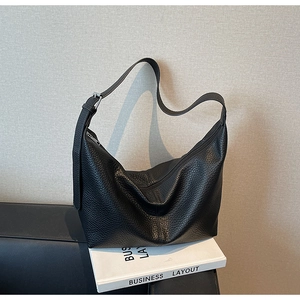 Close-up of black lychee grain leather hobo bag with adjustable wide strap and metal buckle