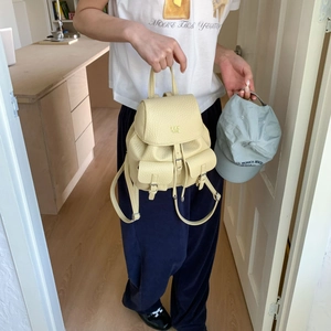 Detail of cream pebbled leather mini backpack with dual front pockets and logo