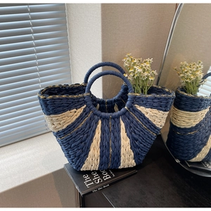 Detail view of woven tote bag with blue and white stripes and gold thread accents