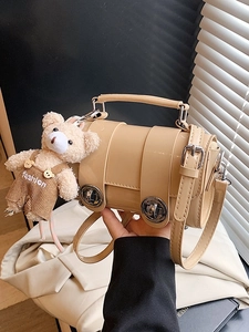 Fashionable khaki cylinder crossbody bag with round metal buckles and a cute bear charm