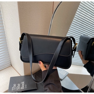 Détail d'un sac sous le bras noir en cuir mat avec boucle dorée et bandoulière réglable