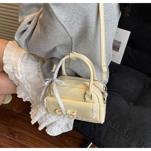 Detail of light yellow bow handbag with lace trim and checkered ribbon on the handle