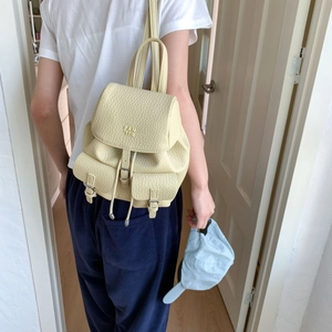 Close-up of creamy pebble leather backpack with drawstring closure and front flap pockets