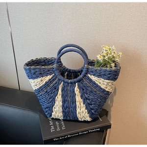 Detail of hand-woven straw tote with blue and beige stripes and gold silk thread accents