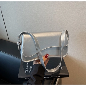 Détail du sac sous le bras argenté brillant avec rabat asymétrique et bandoulière