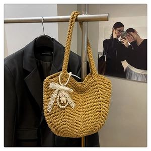 Detail of mustard yellow woven tote bag with lace bow and cute doll charm on hanger