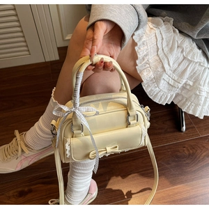 Detail of cream yellow bow handbag with lace trim and grey plaid ribbon handle
