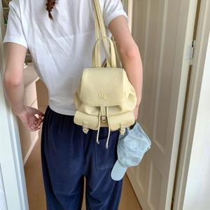 Detail shot of pale yellow pebbled leather backpack with drawstring and Pan Tor logo